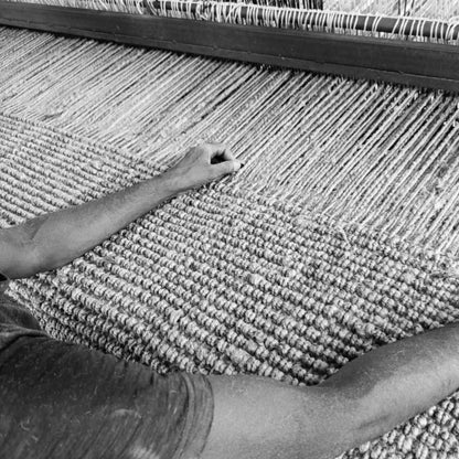 Black and White Image of one of our Indian Makers creating our Rugs on their Rug Looms